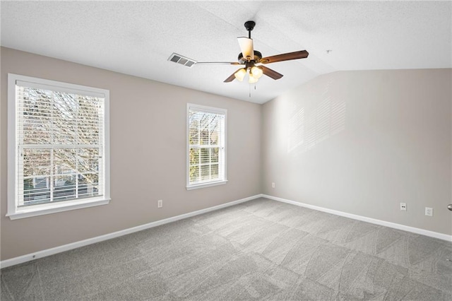 empty room featuring vaulted ceiling, carpet, visible vents, and baseboards