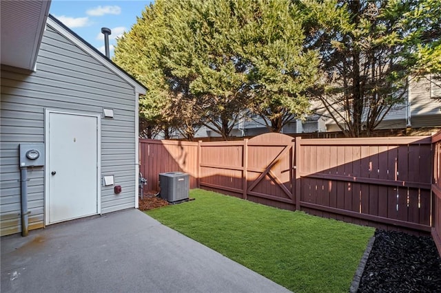 view of yard with a patio, fence, central AC unit, and a gate