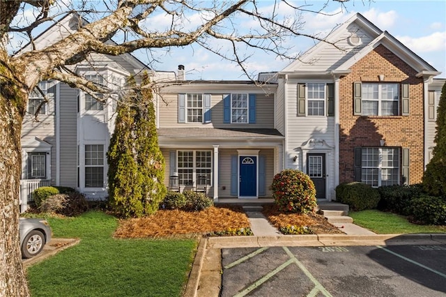 view of front of house with a chimney, a front yard, and uncovered parking