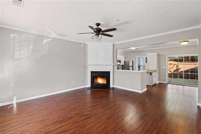 unfurnished living room with visible vents, a textured ceiling, dark wood finished floors, a large fireplace, and crown molding