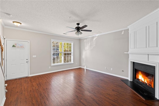 unfurnished living room with a ceiling fan, dark wood-style floors, baseboards, a fireplace, and crown molding