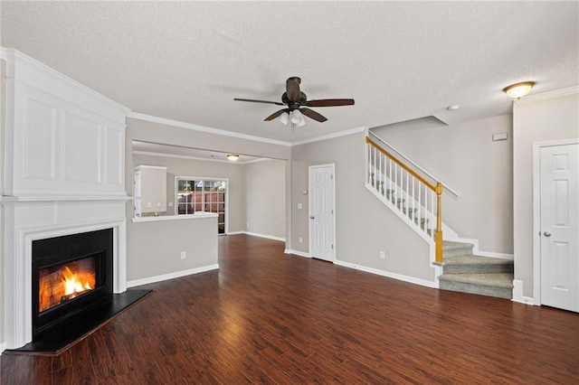 unfurnished living room featuring baseboards, stairway, wood finished floors, a glass covered fireplace, and a ceiling fan