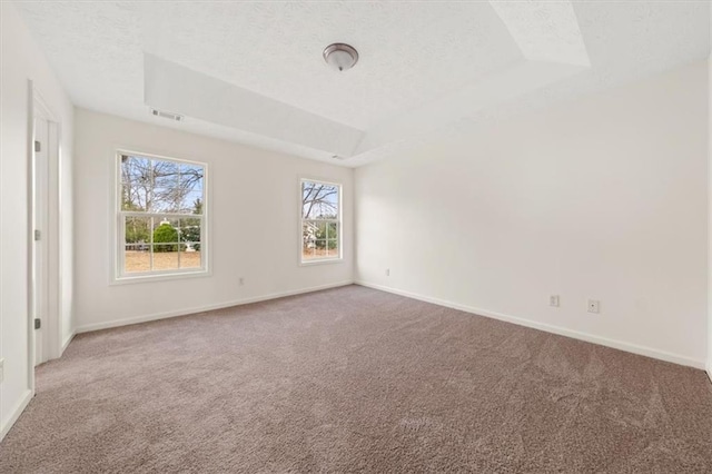 carpeted empty room featuring visible vents, baseboards, a tray ceiling, vaulted ceiling, and a textured ceiling