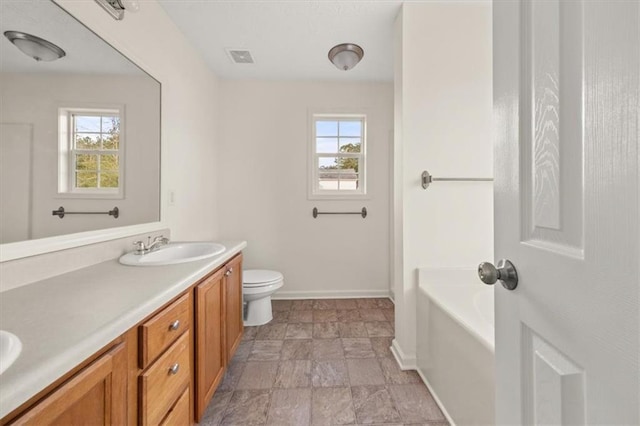 bathroom with a sink, toilet, a healthy amount of sunlight, and double vanity