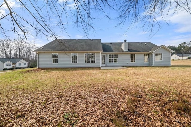 back of property with a patio, a yard, and a chimney