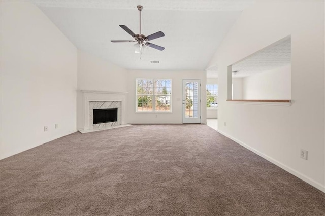 unfurnished living room featuring a high end fireplace, a ceiling fan, carpet flooring, and vaulted ceiling