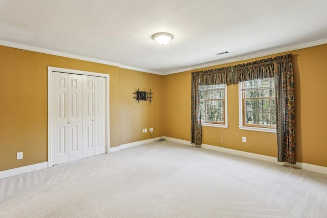 unfurnished bedroom featuring light carpet, crown molding, and a closet