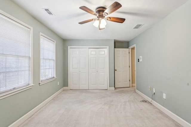 unfurnished bedroom with light carpet, ceiling fan, and a closet