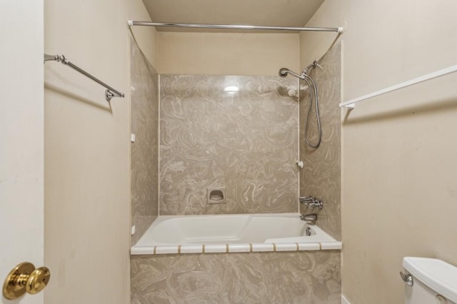 bathroom with toilet and tiled shower / bath