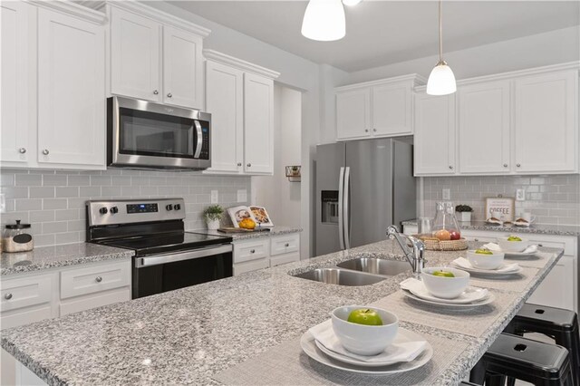 kitchen featuring white cabinets, sink, appliances with stainless steel finishes, tasteful backsplash, and decorative light fixtures