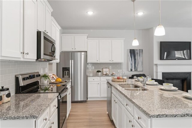 kitchen with appliances with stainless steel finishes, white cabinetry, pendant lighting, and sink