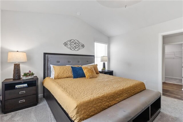 bedroom with light colored carpet, a spacious closet, a closet, and lofted ceiling