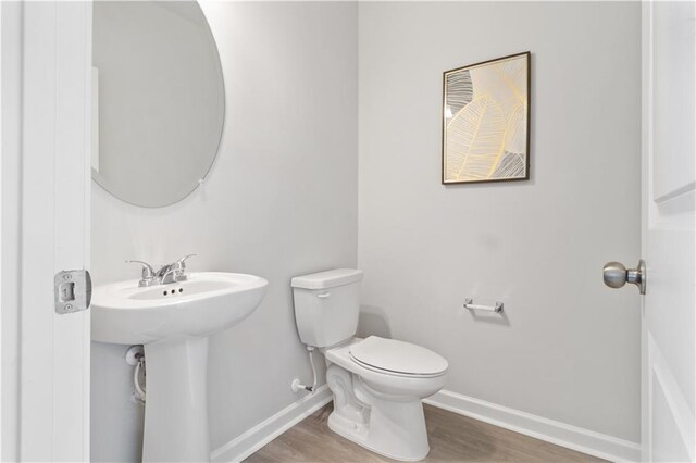 bathroom with toilet, wood-type flooring, and sink