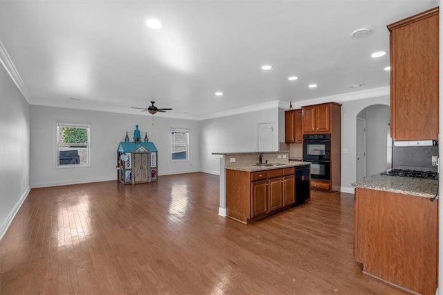 kitchen featuring brown cabinets, black appliances, arched walkways, ceiling fan, and baseboards