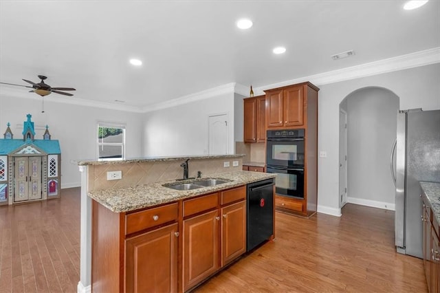 kitchen featuring a sink, black appliances, arched walkways, a kitchen island with sink, and ceiling fan