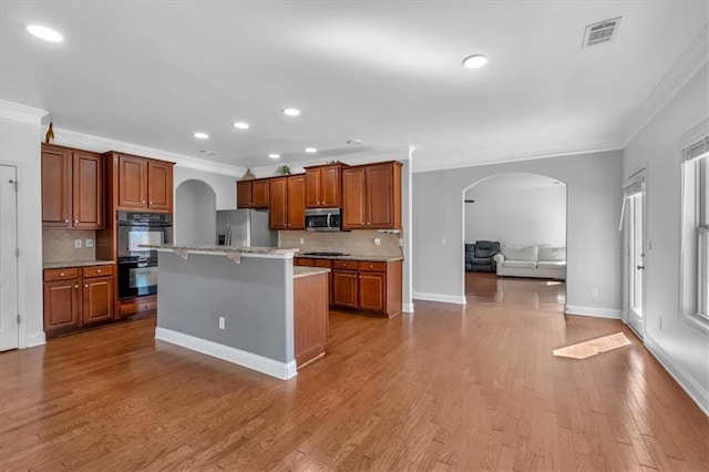 kitchen with stainless steel appliances, arched walkways, crown molding, open floor plan, and backsplash