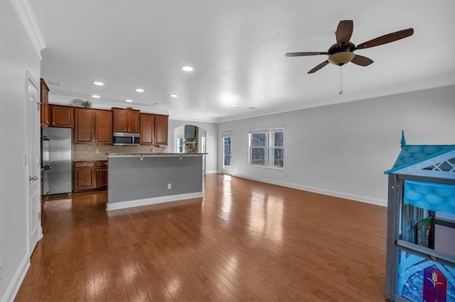 kitchen featuring stainless steel appliances, arched walkways, crown molding, open floor plan, and dark wood-style flooring