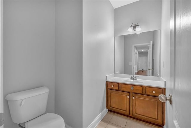 half bath with tile patterned flooring, toilet, vanity, and baseboards