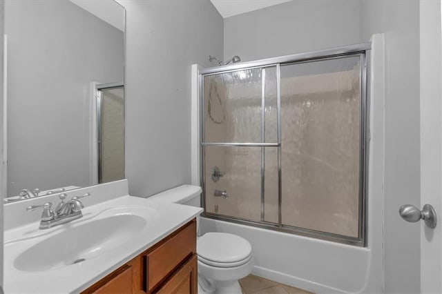 full bathroom featuring toilet, vanity, tile patterned flooring, and bath / shower combo with glass door