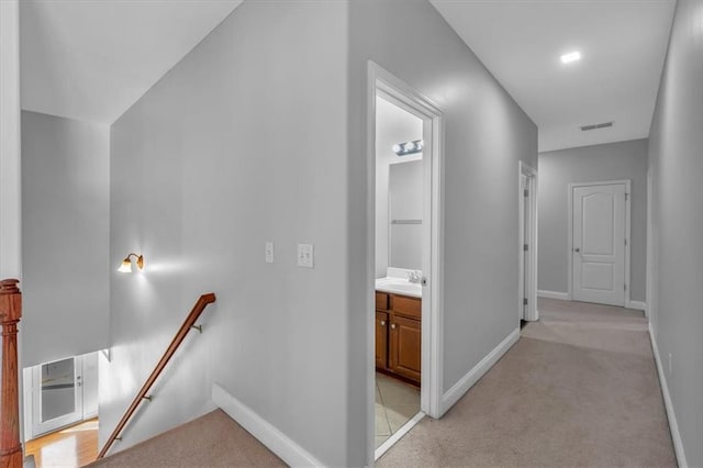 hall featuring an upstairs landing, a sink, light carpet, and baseboards