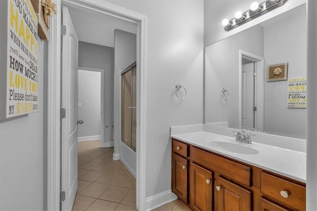 bathroom with tile patterned flooring, vanity, combined bath / shower with glass door, and baseboards
