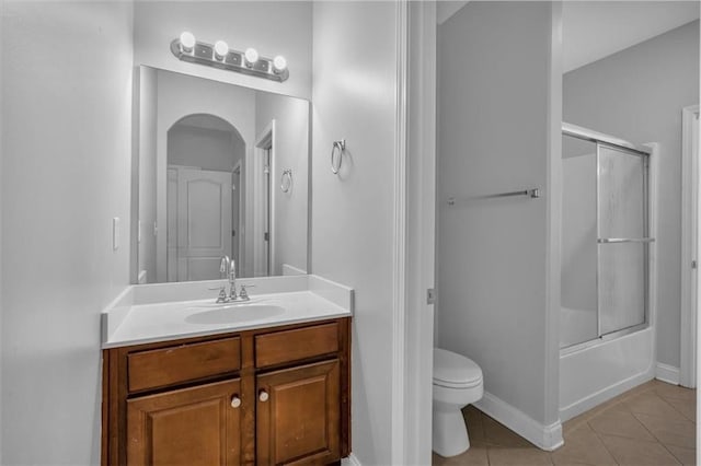 bathroom with tile patterned floors, toilet, vanity, combined bath / shower with glass door, and baseboards