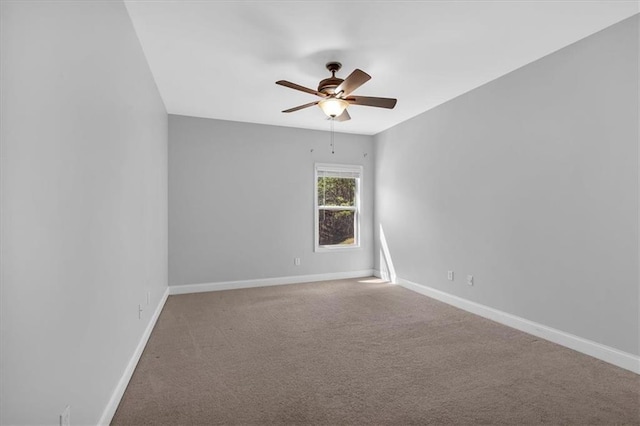spare room featuring a ceiling fan, carpet, and baseboards