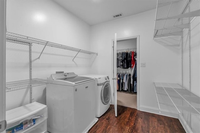 clothes washing area with washing machine and clothes dryer, dark wood finished floors, and baseboards