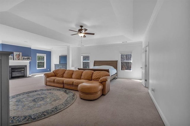 living area with carpet floors, a raised ceiling, ceiling fan, baseboards, and crown molding