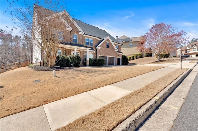 traditional home featuring an attached garage, brick siding, driveway, and a residential view