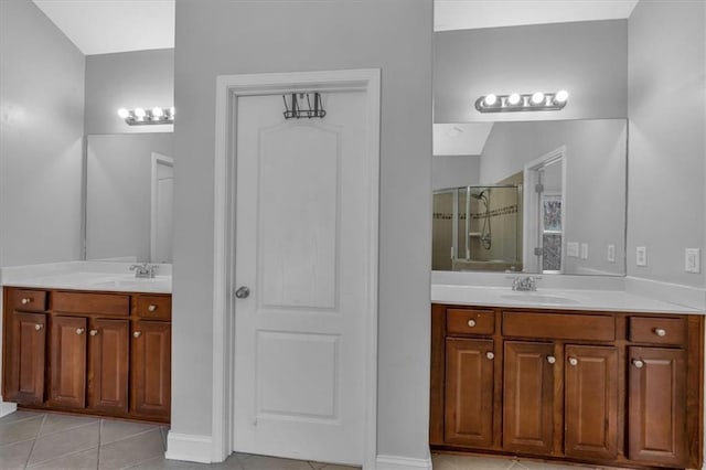 bathroom with a stall shower, tile patterned flooring, two vanities, and baseboards