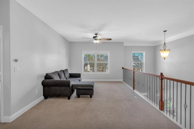 sitting room with a ceiling fan, carpet, baseboards, and crown molding