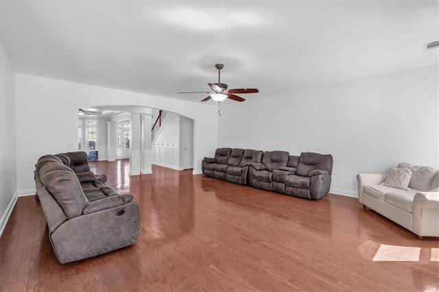 living area with ceiling fan, arched walkways, ornate columns, wood finished floors, and baseboards