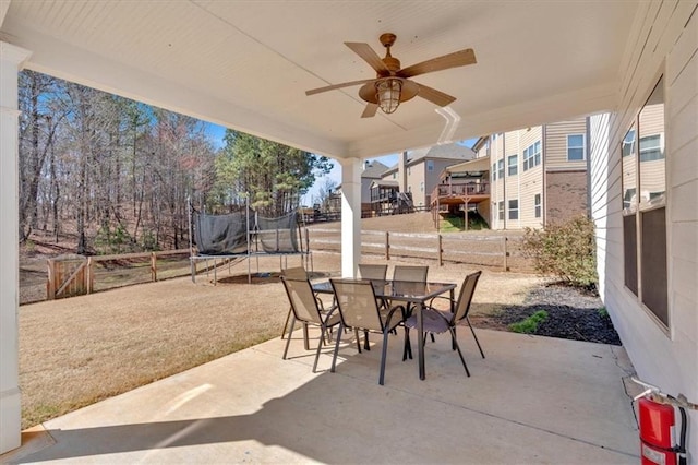 view of patio / terrace featuring a trampoline, outdoor dining area, a fenced backyard, and ceiling fan