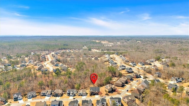 aerial view of property and surrounding area featuring nearby suburban area and a heavily wooded area