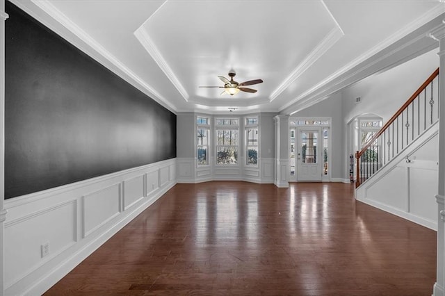 unfurnished living room with ceiling fan, a raised ceiling, a decorative wall, decorative columns, and ornamental molding