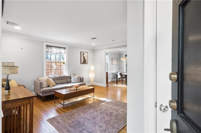 living room featuring ornamental molding and light hardwood / wood-style floors