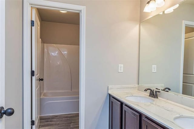 bathroom with double vanity, a sink, wood finished floors, and shower / bath combination