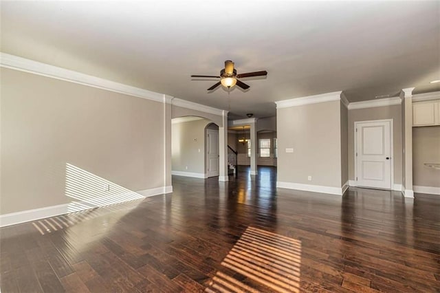 unfurnished living room featuring arched walkways, crown molding, baseboards, a ceiling fan, and dark wood-type flooring