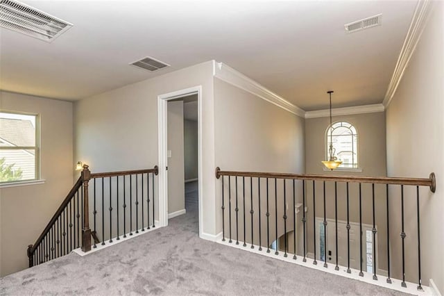 hall with an upstairs landing, visible vents, and carpet flooring
