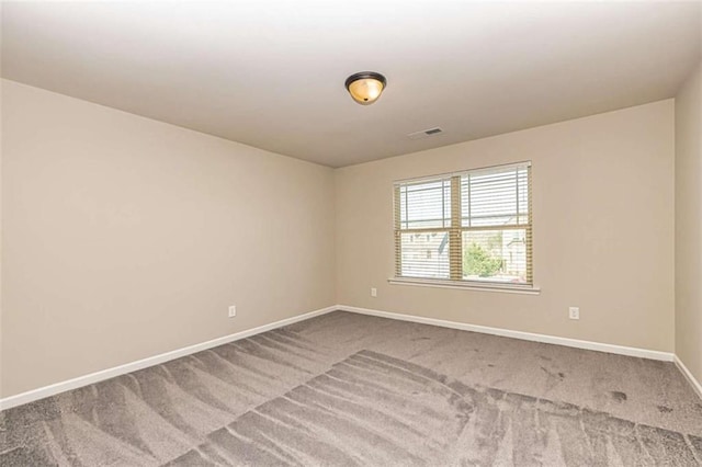 spare room featuring visible vents, carpet flooring, and baseboards
