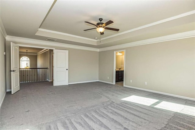 empty room featuring carpet, a ceiling fan, a tray ceiling, and crown molding