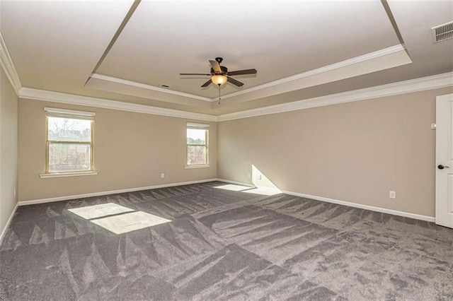 carpeted empty room featuring crown molding, a raised ceiling, visible vents, baseboards, and a ceiling fan