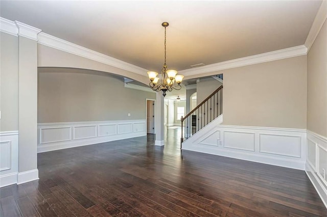 unfurnished dining area featuring stairway, a chandelier, dark wood-type flooring, arched walkways, and wainscoting