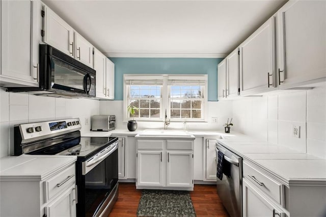 kitchen with sink, dark wood-type flooring, appliances with stainless steel finishes, white cabinets, and decorative backsplash