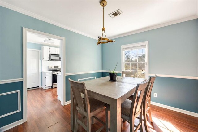 dining space with dark hardwood / wood-style flooring, crown molding, and ceiling fan with notable chandelier