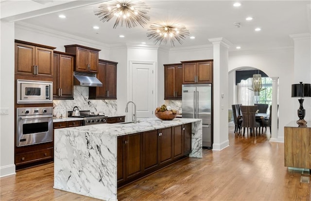 538 Sarabrook Pl, Sandy Springs, GA 30342 - kitchen featuring built in appliances, arched walkways, a chandelier, under cabinet range hood, and backsplash