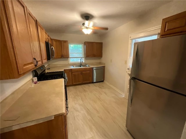 kitchen with appliances with stainless steel finishes, light wood-type flooring, ceiling fan, and sink