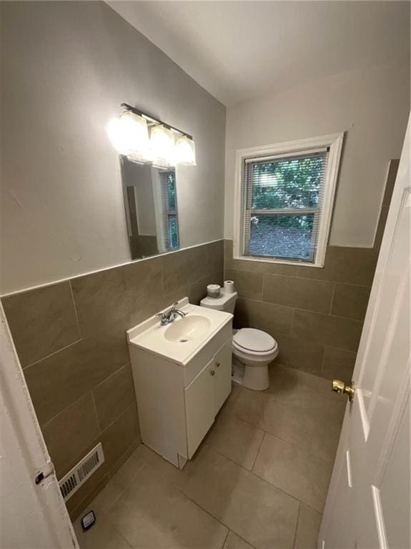 bathroom featuring tile patterned flooring, vanity, toilet, and tile walls