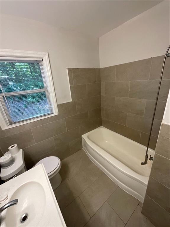 full bathroom with sink, tile patterned flooring, toilet, tile walls, and shower / bathtub combination